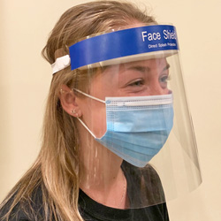 person wearing a disposable face shield and surgical style mask