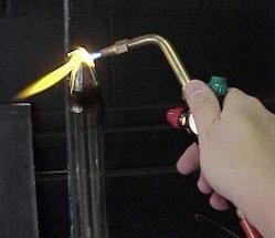 a hand-held torch being used on a stationary piece of glass